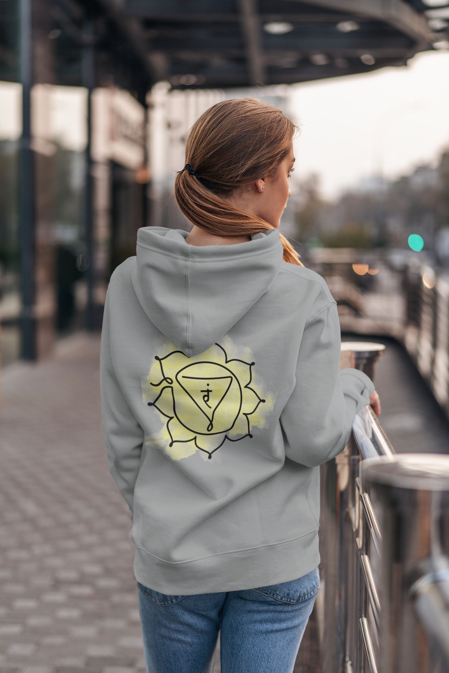 Wearing a gray hoodie with a Manipura chakra design on the back. Adventure-ready comfort by Inkasis.