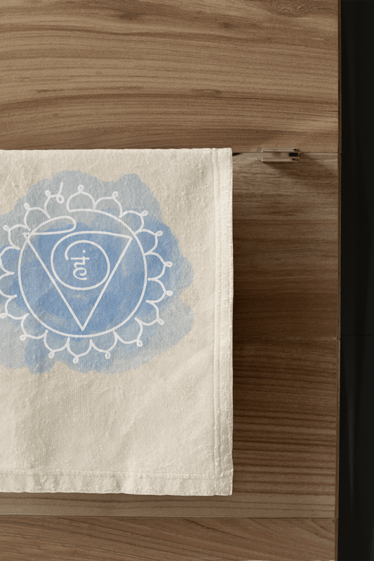  "Throat Chakra hand towel with Vishuddha symbol, fostering clear communication, hanging in a sleek bathroom